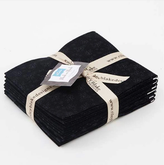 A bundle of black fat quarters with tonal prints, tied together with a ribbon and a tag displaying the brand name 'Riley Blake Designs'.
Photo by RileyBlakeDesigns.com [image_link]
