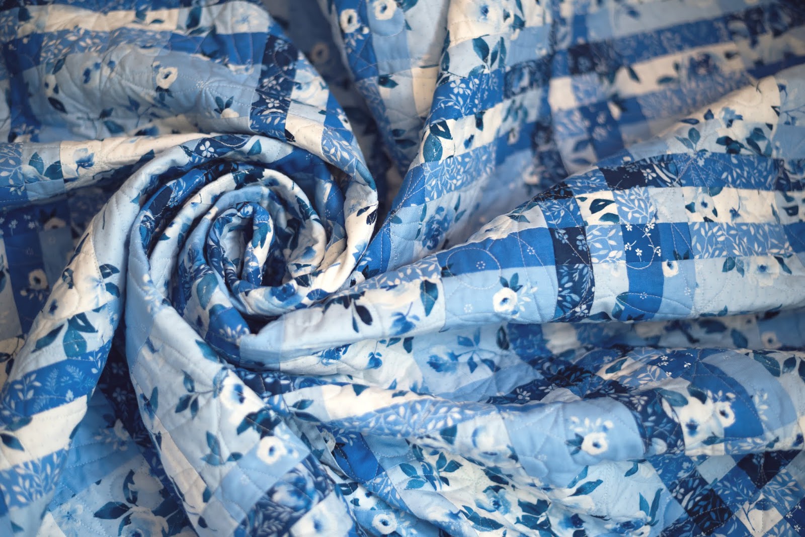 A quilt featuring a blue and white geometric pattern resembling a woven shawl.
Photo by Briar Hill Designs [additional_image_link]