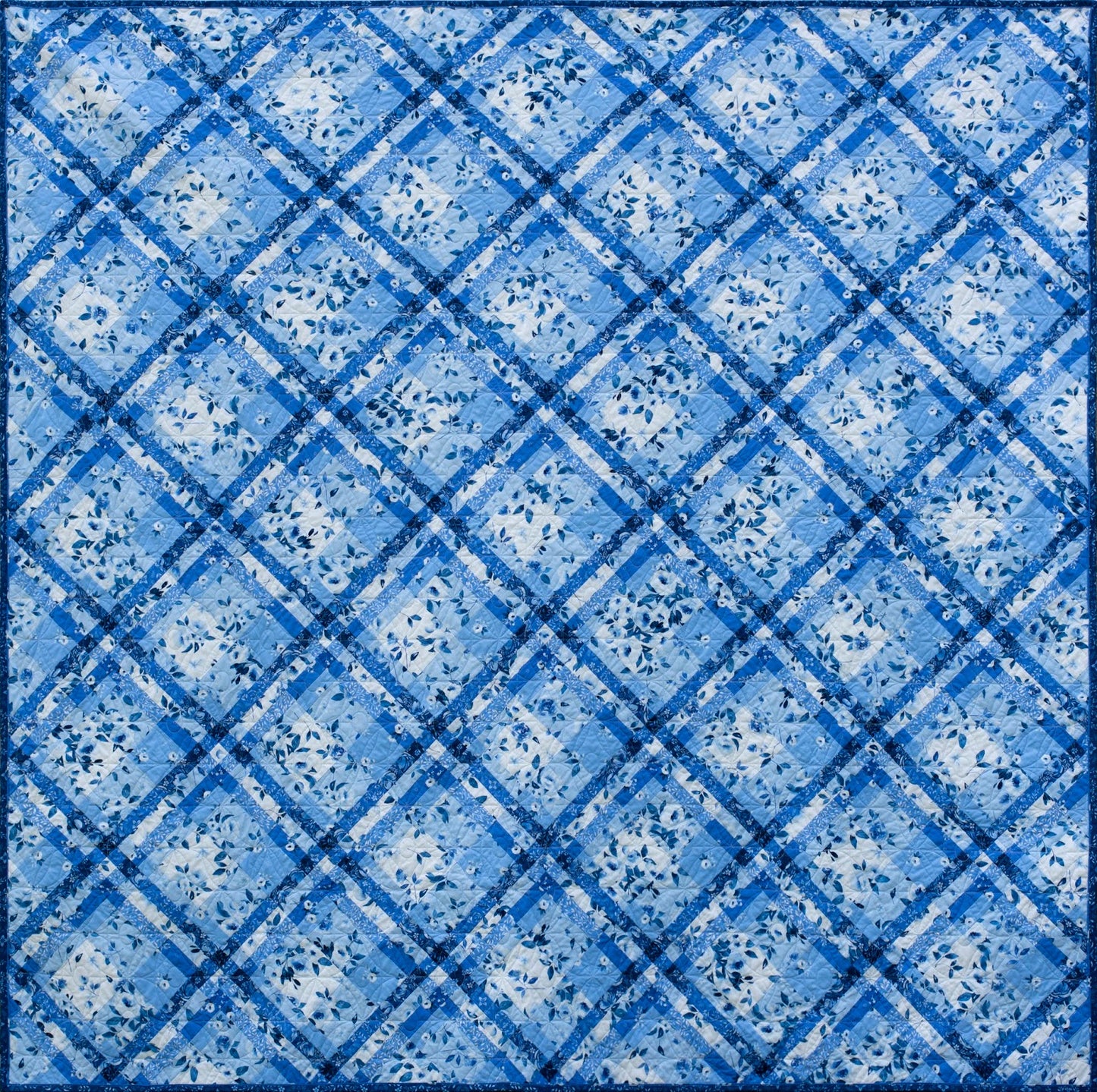 A quilt featuring a blue and white geometric pattern resembling a woven shawl.
Photo by Briar Hill Designs [additional_image_link]