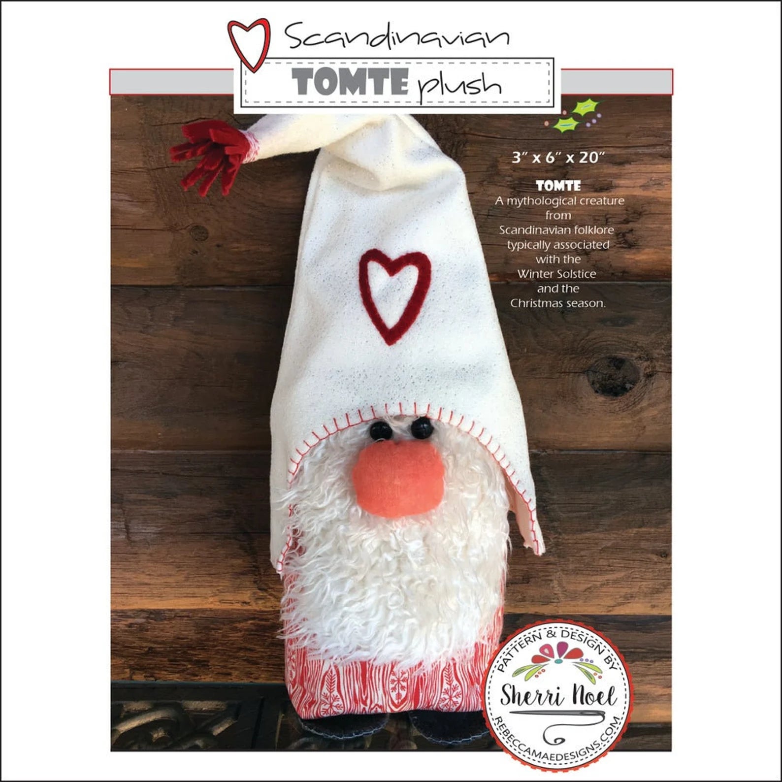 A handmade felt gnomehat ornament labeled 'TOMTE plush' on a wooden background, with text showing dimensions and a Sherri Hoel anniversary badge. The hat is off-white with a red heart, red stitched trim, a red nose, and red-and-white patterned cuffs.
Photo by Sherri Noel [additional_image_link]