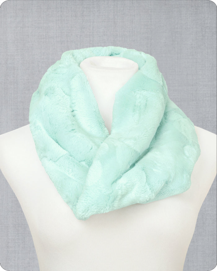 A sea glass green faux fur infinity scarf displayed on a white mannequin bust against a textured gray background.
Photo by Shannon Fabrics [image_link]