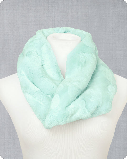 A sea glass green faux fur infinity scarf displayed on a white mannequin bust against a textured gray background.
Photo by Shannon Fabrics [image_link]