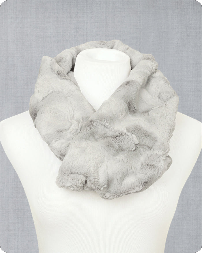 A light gray faux fur infinity scarf draped on a white mannequin torso against a textured gray background. 
Photo by Shannon Fabrics [image_link]