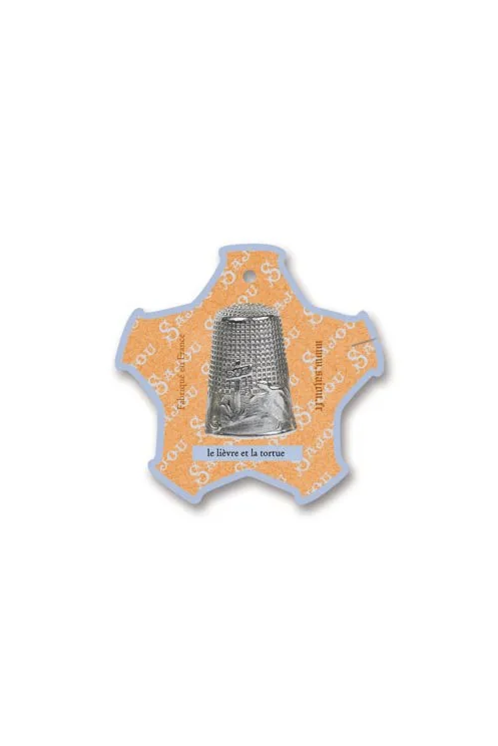 A small decorative thread card shaped like a star, featuring a silver thimble illustration in the center on a pale yellow and white background, placed on a white surface.
Photo by Sajou.fr [additional_image_link]