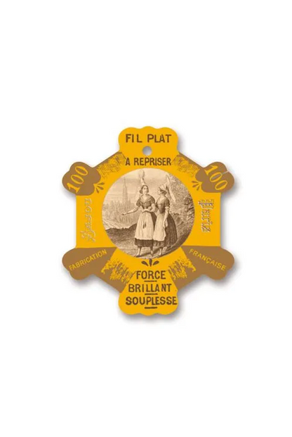 A vintage French sewing thread spool tthread card for 'Fil Plat' thread, featuring a yellow and brown star-shaped design with an illustration of two women sewing.
Photo by Sajou.fr [additional_image_link]