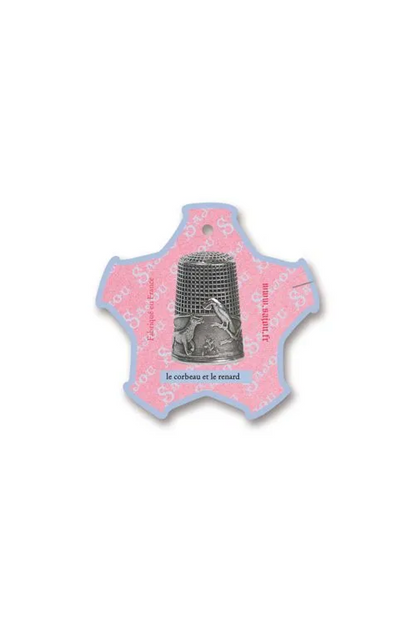 A small decorative thread card shaped like a five-pointed star, featuring a pink center with a silver thimble illustration and French text, placed on a white background.
Photo by Sajou.fr [additional_image_link]