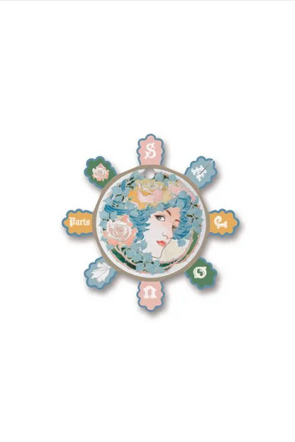 A vintage-style circular thread card with eight petal-like extensions, featuring an illustrated face with blue hair and pastel floral details, displayed on a white background.
Photo by Sajou.fr [additional_image_link]