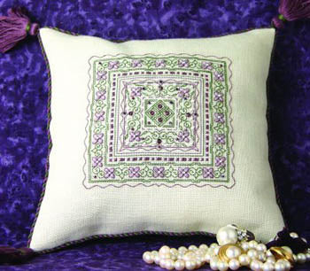 Cross stitch embroidery pillow with a geometric violet pattern, featuring a three-dimensional sheen and adorned with beads on a purple background.
Photo by The Sweetheart Tree [image_link]