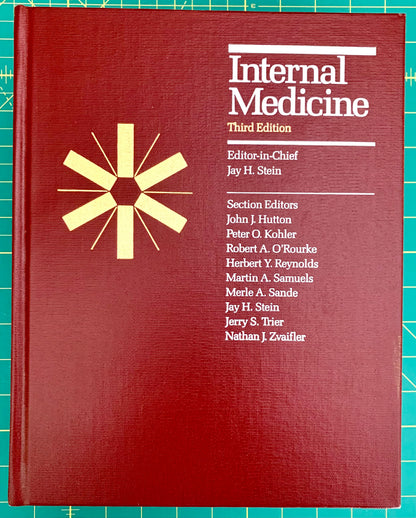 A hardcover book titled 'Internal Medicine Third Edition' with a dark red cover, white text, and a gold starburst emblem, photographed on a green cutting mat background.
[image_link]