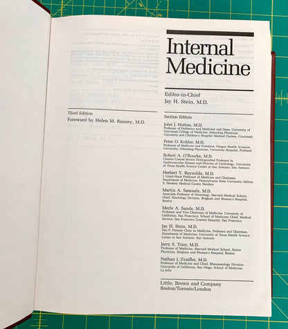 An open book showing the interior front cover of a volume titled 'Internal Medicine' with editorial and publisher text, photographed from above on a green cutting mat.
[additional_image_link]