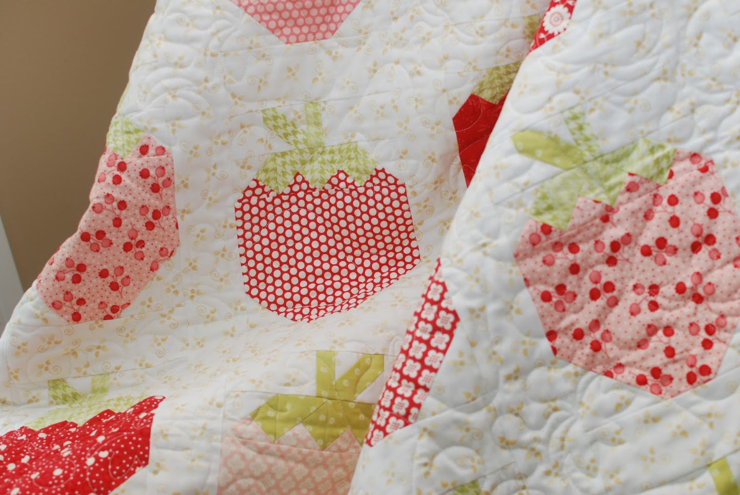 A close-up of a quilted fabric featuring a strawberry pattern in red, pink, and light green on a white background.
Photo by ThePatternBasket.com [additional_image_link]