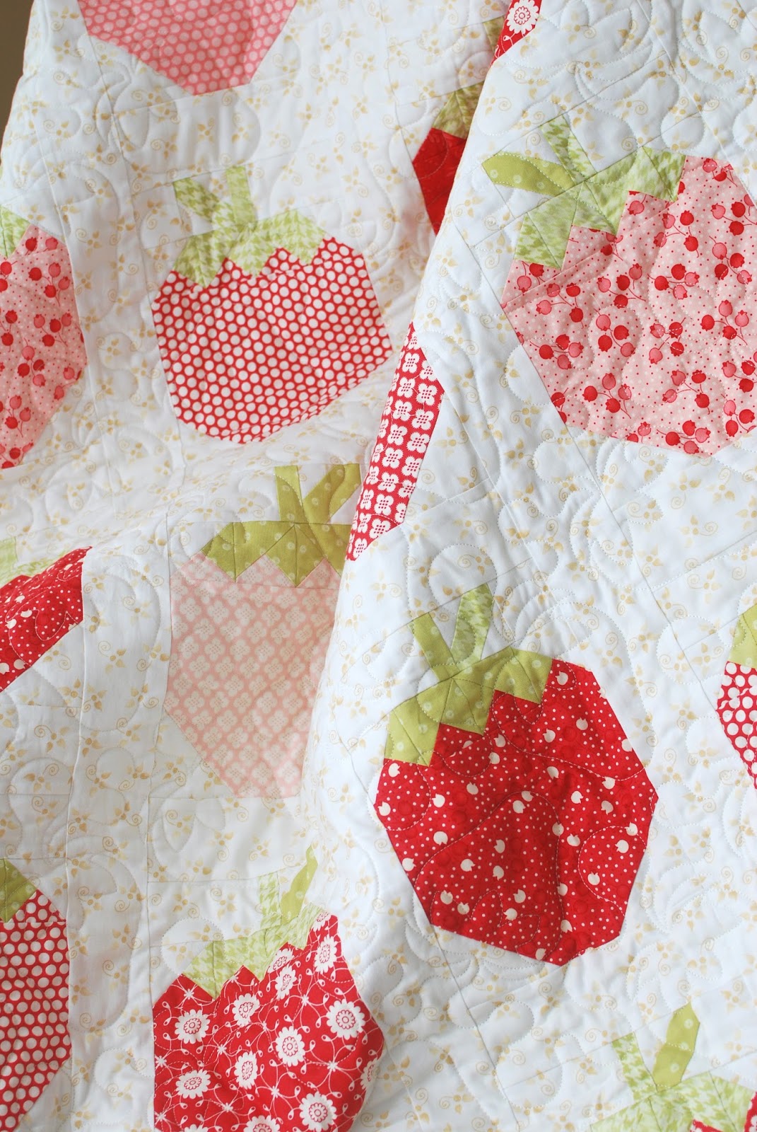 A close-up of a quilted fabric featuring a strawberry pattern in red, pink, and light green on a white background.
Photo by ThePatternBasket.com [additional_image_link]