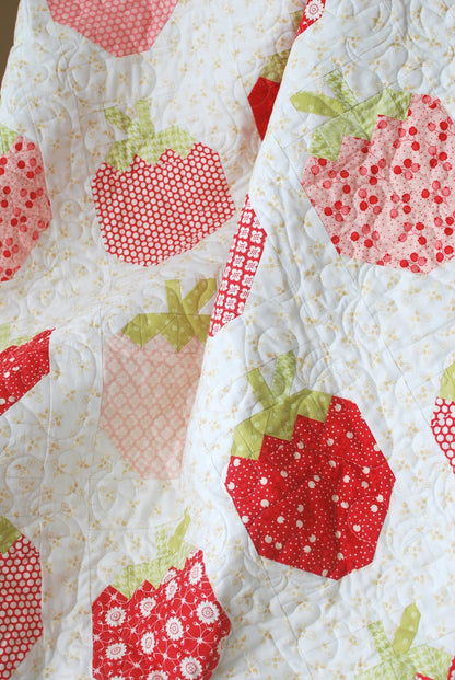 A close-up of a quilted fabric featuring a strawberry pattern in red, pink, and light green on a white background.
Photo by ThePatternBasket.com [additional_image_link]