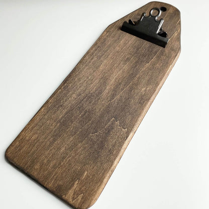 A dark brown wooden clipboard with a black metal clip at the top, photographed on a plain white background.
Photo by HandsOnDesign.biz [additional_image_link]