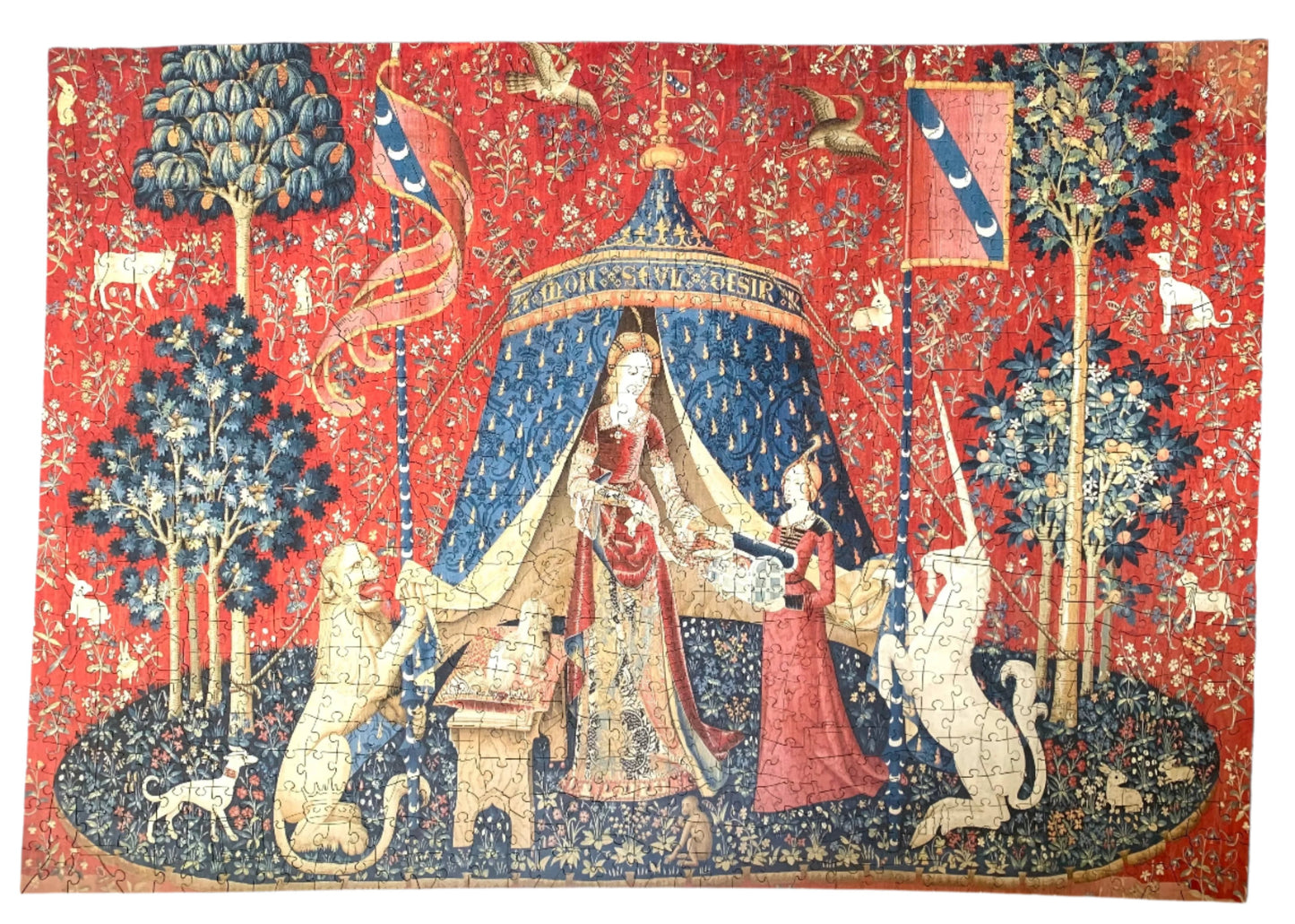 A completed wooden jigsaw puzzle depicting a medieval-style tapestry scene with a figure, animals, and decorative elements in red, blue, and natural wood colors.
Photo by Karen King [additional_image_link]