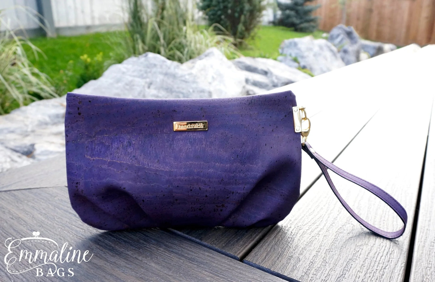 Purple handbag with a visible brand logo on a wooden surface outdoors.
Photo by Emmaline Bags [additional_image_link]
