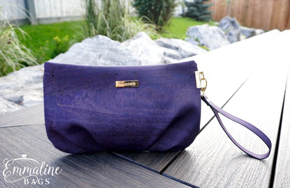 Purple handbag with a visible brand logo on a wooden surface outdoors.
Photo by Emmaline Bags [additional_image_link]