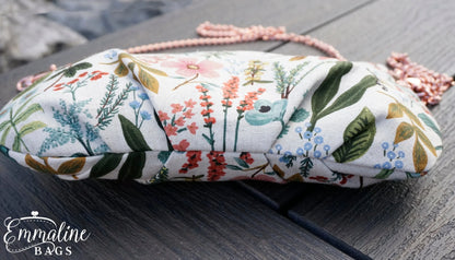 Floral patterned pouch with tassels on a wooden surface, featuring the brand 'Emmaline Bags'.
Photo by Emmaline Bags [additional_image_link]