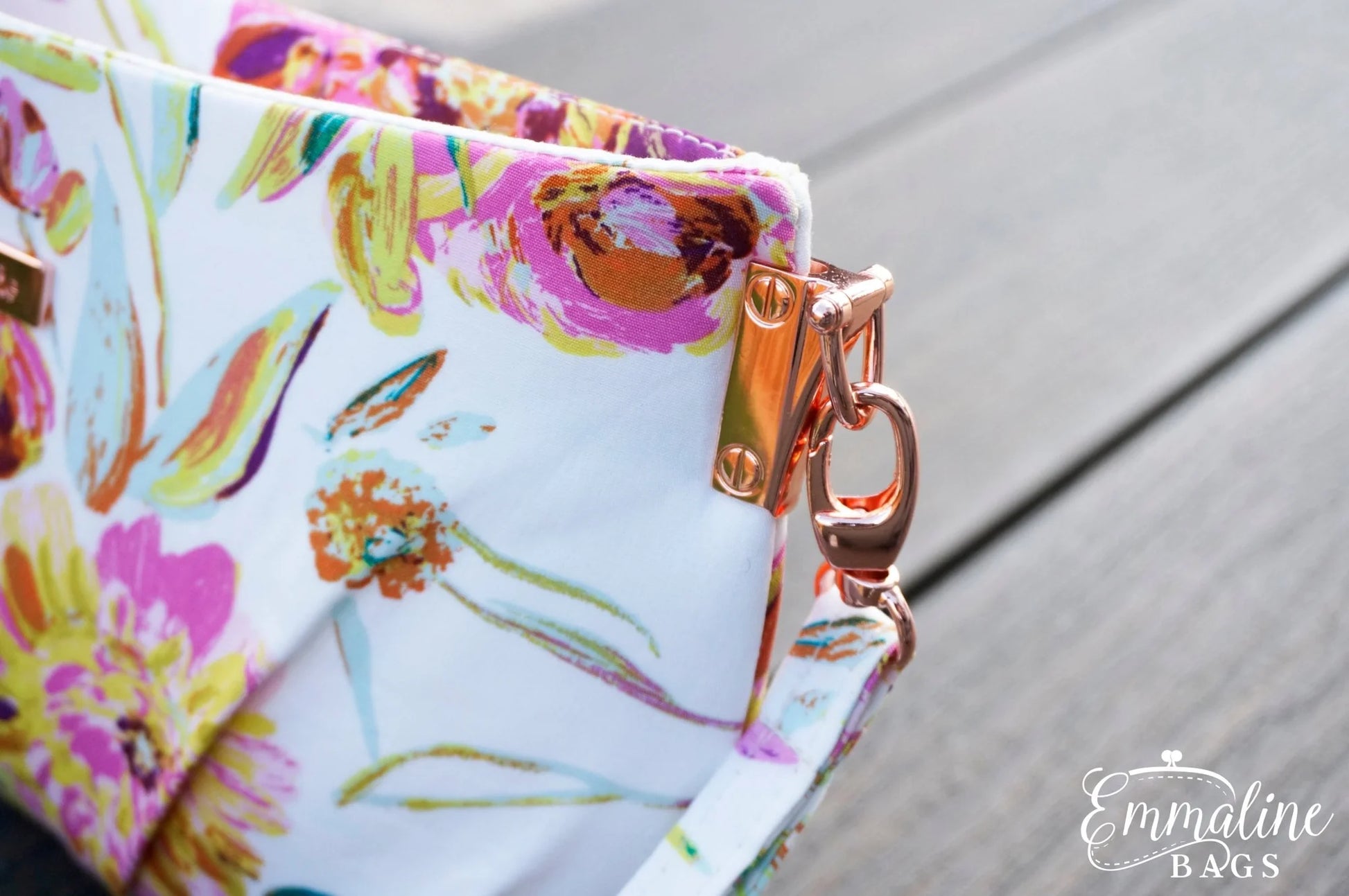 Floral-patterned bag with a gold clasp on a wooden surface, featuring the brand 'Emmaline Bags'.
Photo by Emmaline Bags [additional_image_link]