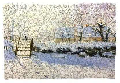 A jigsaw puzzle depicting a winter scene with a path, fence, and trees, predominantly in shades of white and blue by Claude Monet.
Photo by Karen King [additional_image_link]