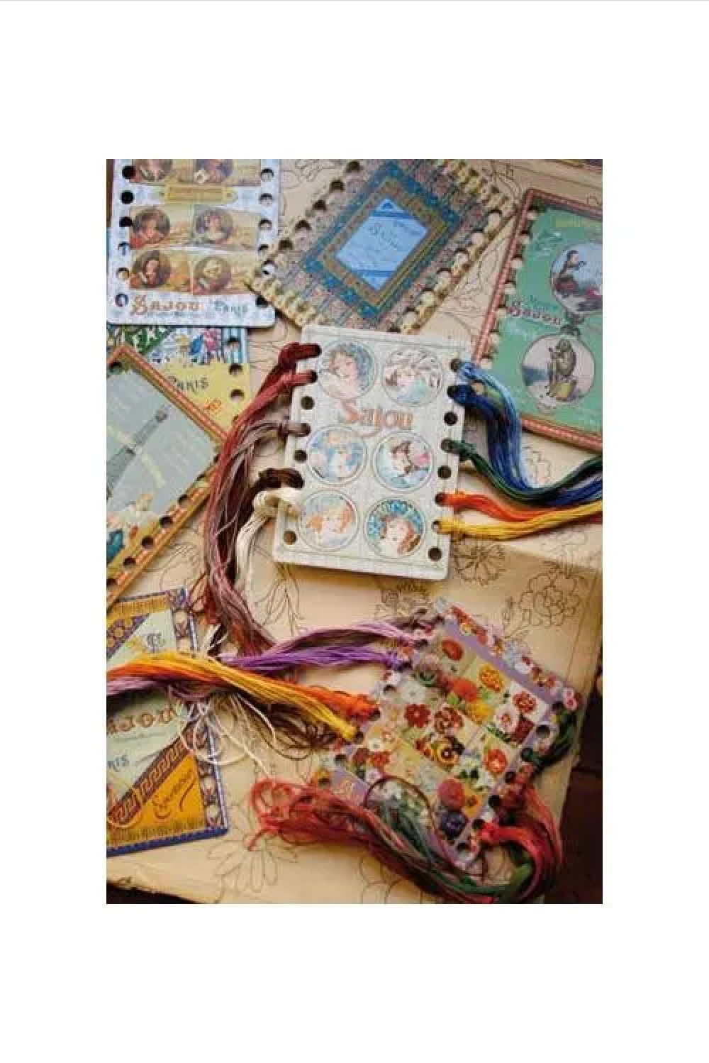 A collection of vintage-style handmade craft embellishments, thread organizers, including embroidered patches, colorful thread bundles, and decorative paper pieces arranged on a beige background.
Photo by Sajou.fr [additional_image_link]