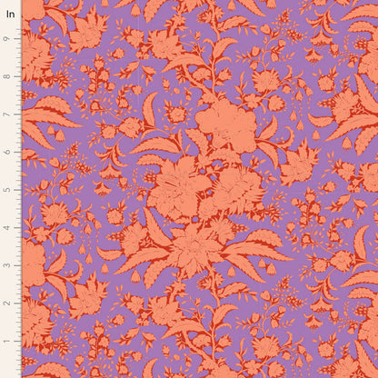 A close-up of a floral fabric pattern with coral-orange flowers and leaves on a lavender-purple background, shown with a white ruler along the left edge for scale.
Photo by Tildafabrics.com [image_link]