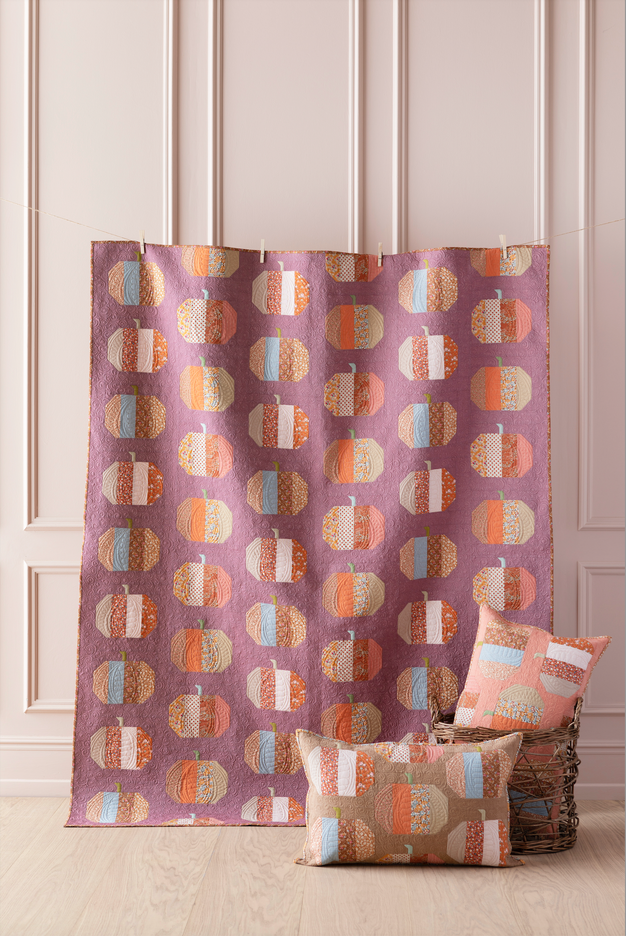 A purple curtain panel with a repeating pattern of stylized pumpkins in orange, beige, and light blue, hanging in a room with a wicker basket and matching pillows on a light wood floor.
Photo by Tildafabrics.com [image_link]