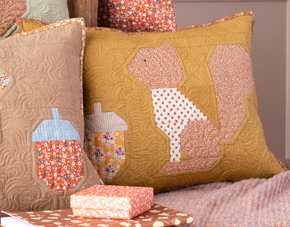 Two decorative quilted throw pillows displayed together on a bed or sofa. The larger pillow is mustard yellow with a squirrel applique made of pink, peach, and white polka-dot fabric.
Photo by Tildafabrics.com [additional_image_link]