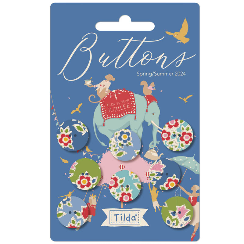Packaging of Tilda Jubilee Fabric Covered Buttons featuring 8 5/8 inch blue and green floral patterned buttons with a festive design, including an illustration of a mouse holding a flag and a elephant, against a blue background.
Photo by Tildafabrics.com [image_link]
