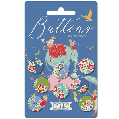 Packaging of Tilda Jubilee Fabric Covered Buttons featuring 8 5/8 inch blue and green floral patterned buttons with a festive design, including an illustration of a mouse holding a flag and a elephant, against a blue background.
Photo by Tildafabrics.com [image_link]