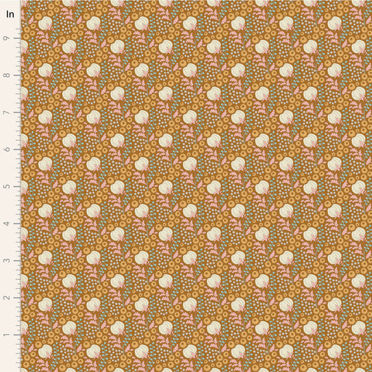 A close-up of a patterned fabric sample with a repeating floral design on a warm mustard background. The pattern includes cream flowers, pink leaves, and small blue-green dots, with a white measurement ruler along the left edge marked in inches.
Photo by Tildafabrics.com [image_link]