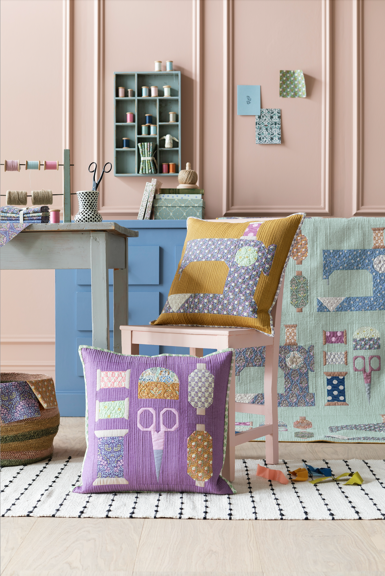 A styled interior scene showing two patchwork throw pillows in a sewing-room setting. One pillow is lavender with sewing machine and thread spool motifs, and the other is mustard yellow with a blue patterned design.
Photo by Tildafabrics.com [additional_image_link]