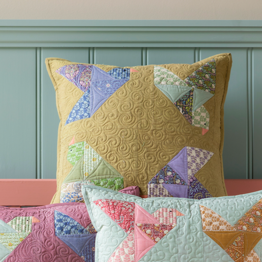 A colorful patchwork bird-patterned quilted throw pillow with a moss background.
Photo by Tildafabrics.com [image_link]