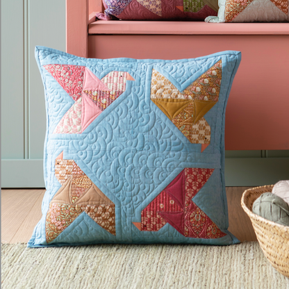 A woman holds a quilted square pillow with patchwork bird designs, and the pillow in petrol.
Photo by Tildafabrics.com [image_link]