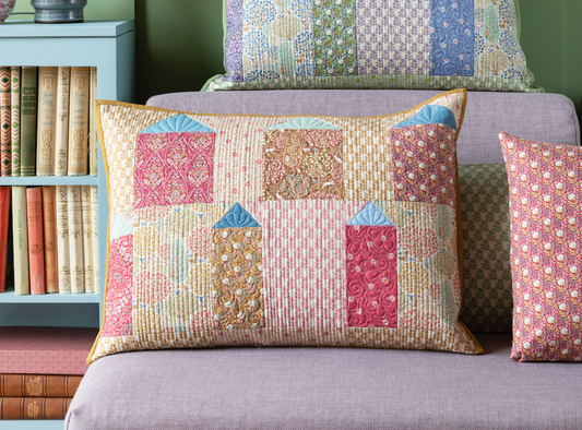 A pillow with a geometric pattern featuring small houses in warm colors.
Photo by Tildafabrics.com [image_link]