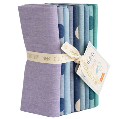 A bundle of folded woven fabrics in various summer blue colors, tied together with a label that reads 'Tilda Quilt Collection'.
Photo by Tildafabrics.com [image_link]