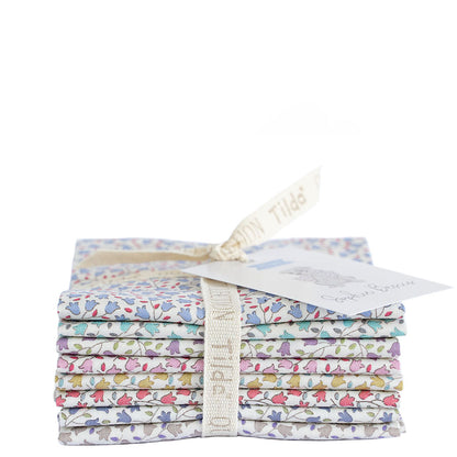A stack of folded patterned fabric pieces tied with a cream ribbon and tag, photographed on a plain white background.
Photo by Tildafabrics.com [additional_image_link]