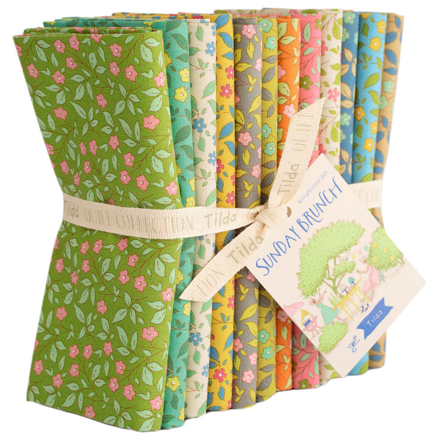 A bundle of folded fabric slices tied with a ribbon and tag, showing multiple floral and botanical pattern designs in green, pink, yellow, blue, and orange on a white background.
Photo by Tildafabrics.com [additional_image_link]
