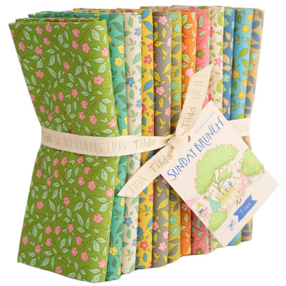 A bundle of folded fabric slices tied with a ribbon and tag, showing multiple floral and botanical pattern designs in green, pink, yellow, blue, and orange on a white background.
Photo by Tildafabrics.com [additional_image_link]