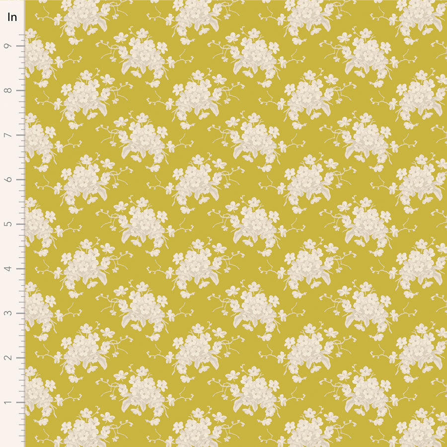 A fabric from the Tilda Sunday Brunch collection featuring a white flower sour yellow pattern on a yellow background, with a visible measuring tape indicating the fabric's scale.
Photo by Tildafabrics.com [image_link]