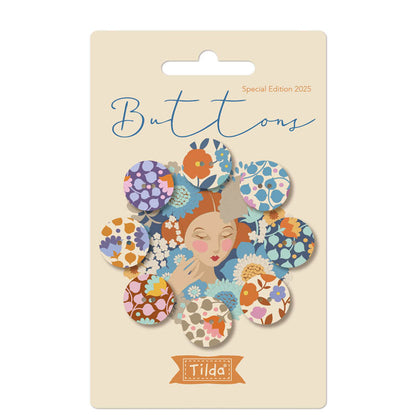 Packaging of Tilda Wallflower Buttons featuring blue and purple fabric covered buttons with floral patterns, name and count indicated on the front.
Photo by Tildafabrics.com [image_link]