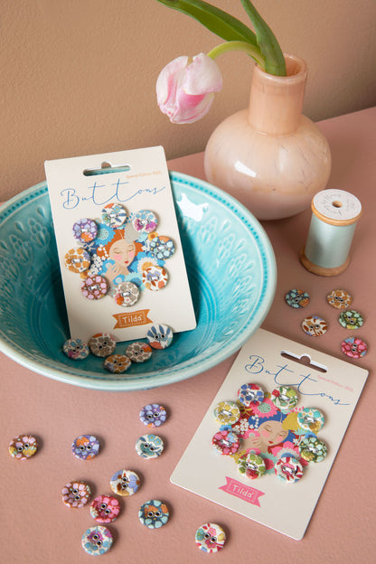 Colorful floral buttons in a blue bowl with a pink vase and spool of thread.
Photo by Tildafabrics.com [additional_image_link]