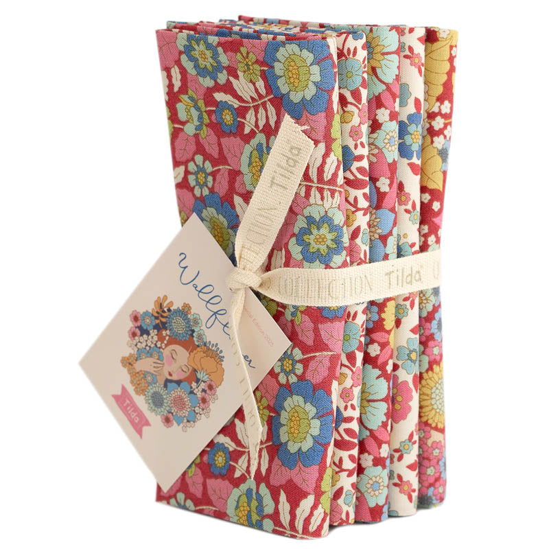 Five fat quarter bundles of Tilda Wallflower fabric with floral patterns in various red colors, tied together with a tag displaying the brand and product name.
Photo by Tildafabrics.com [additional_image_link]