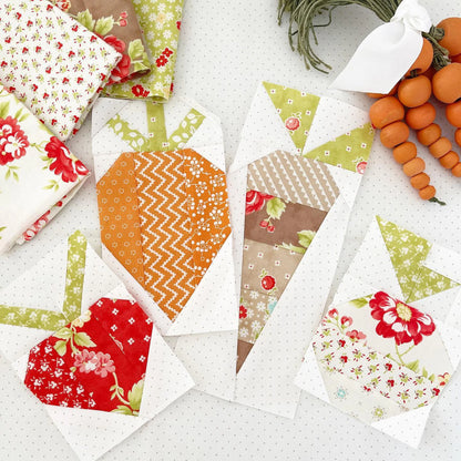 A styled flat-lay of several quilted fabric pumpkin patches arranged on a white polka-dot surface, with decorative pumpkins and a white ribbon in the upper right corner.
Photo by ThePatternBasket.com [additional_image_link]