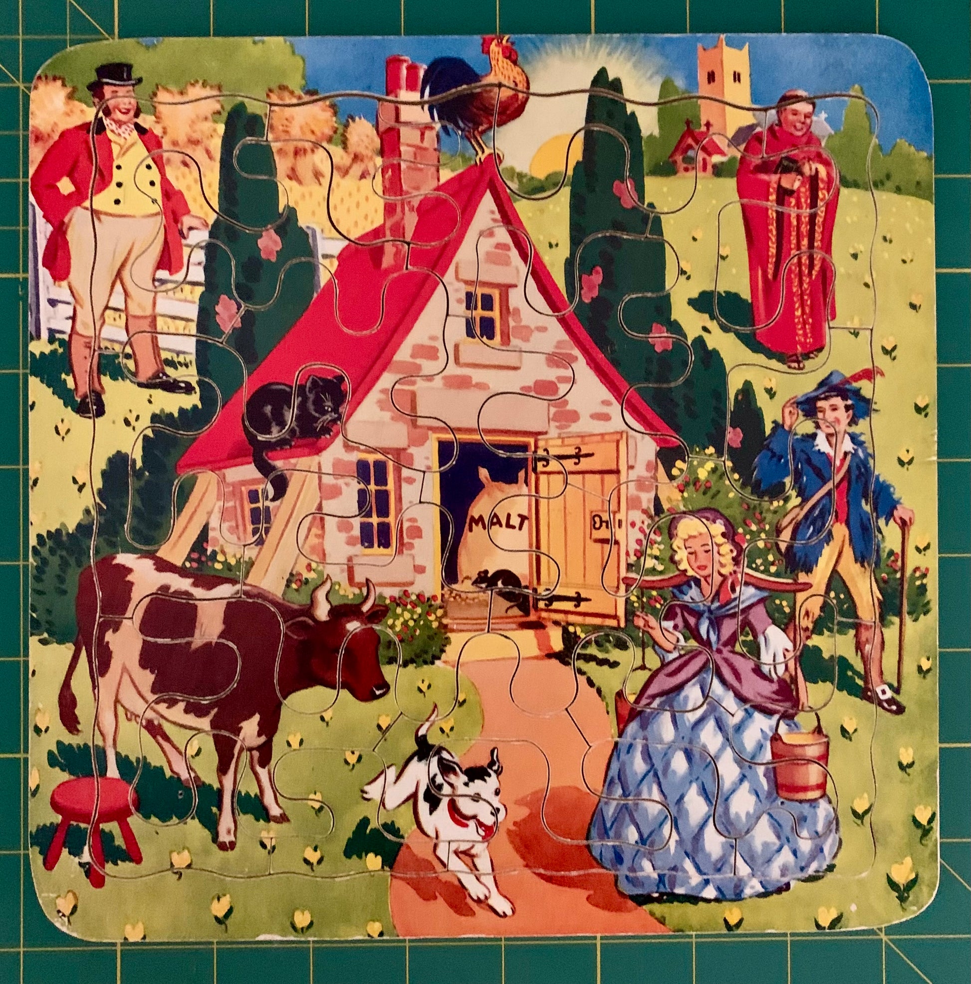 A completed vintage-style wooden puzzle featuring a colorful countryside scene with a small house, people in period clothing, cows, a dog, and a rooster, photographed.
Photo by Karen King [additional_image_link]