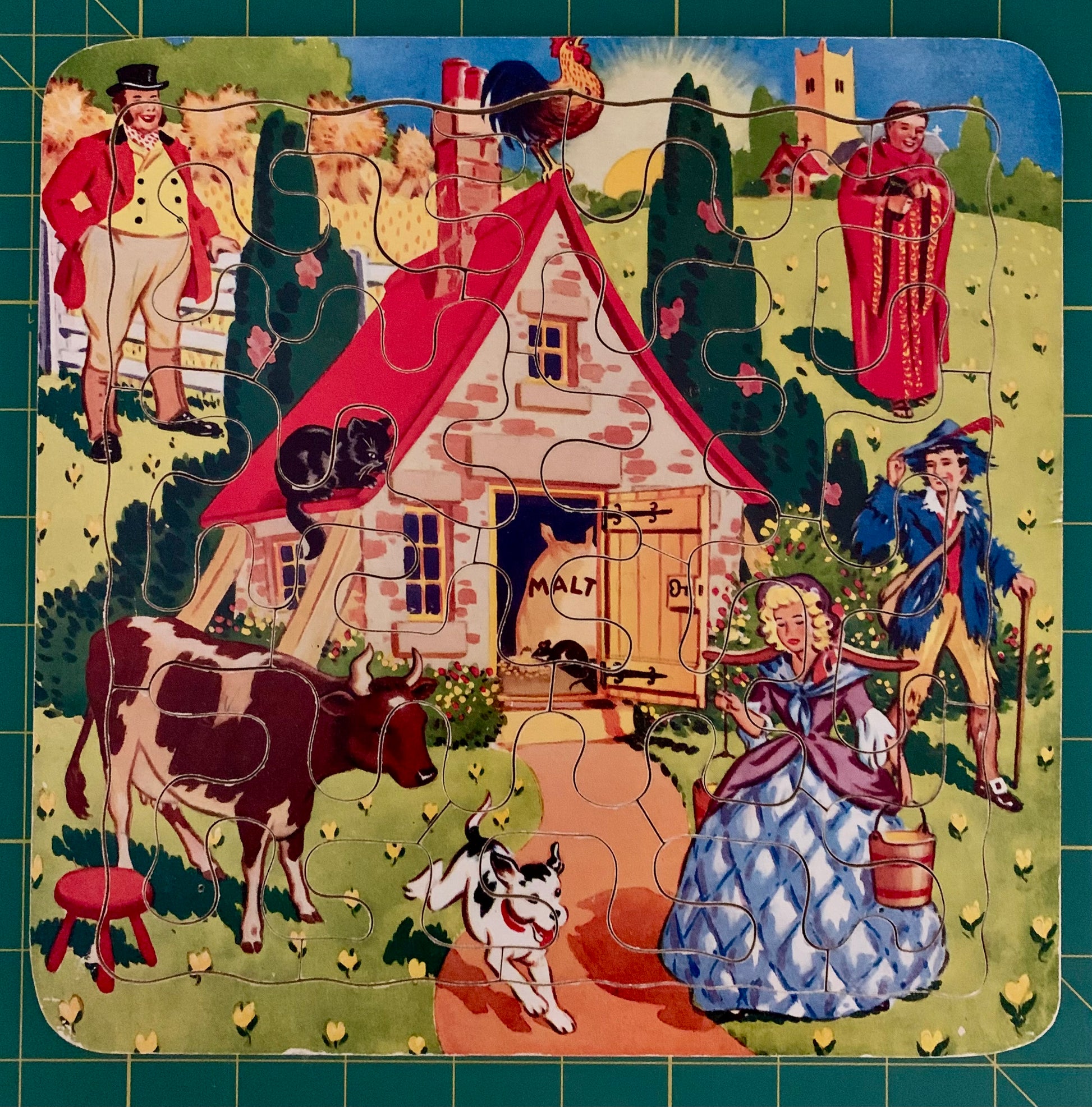 A completed vintage-style illustrated puzzle showing a small cottage with people, animals, and a rooster, set against a green gridded background.
Photo by Karen King [additional_image_link]
