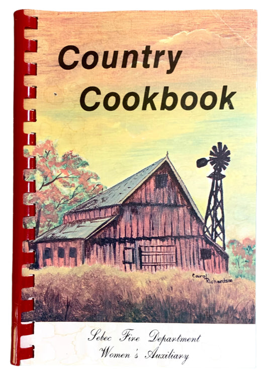 Cover of a vintage country cookbook with a spiral binding featuring an illustration of an old wooden barn and a windmill.
Photo by Karen King [image_link]