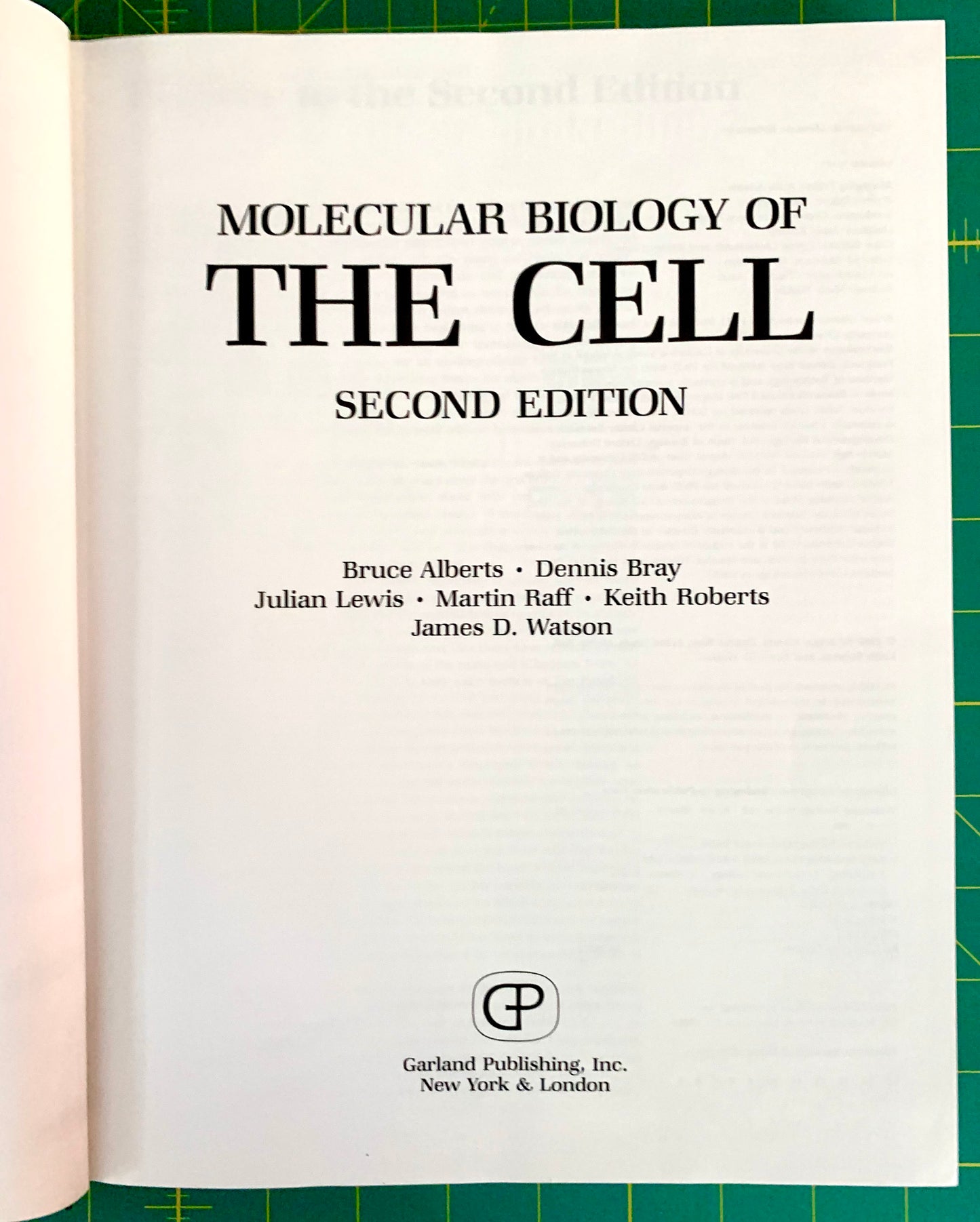 A book page from the front of 'Molecular Biology of the Cell, Second Edition' showing the title page with author names and the Garland Publishing logo, photographed against a green cutting mat background.
[additional_image_link]