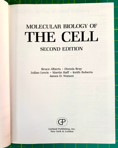 A book page from the front of 'Molecular Biology of the Cell, Second Edition' showing the title page with author names and the Garland Publishing logo, photographed against a green cutting mat background.
[additional_image_link]