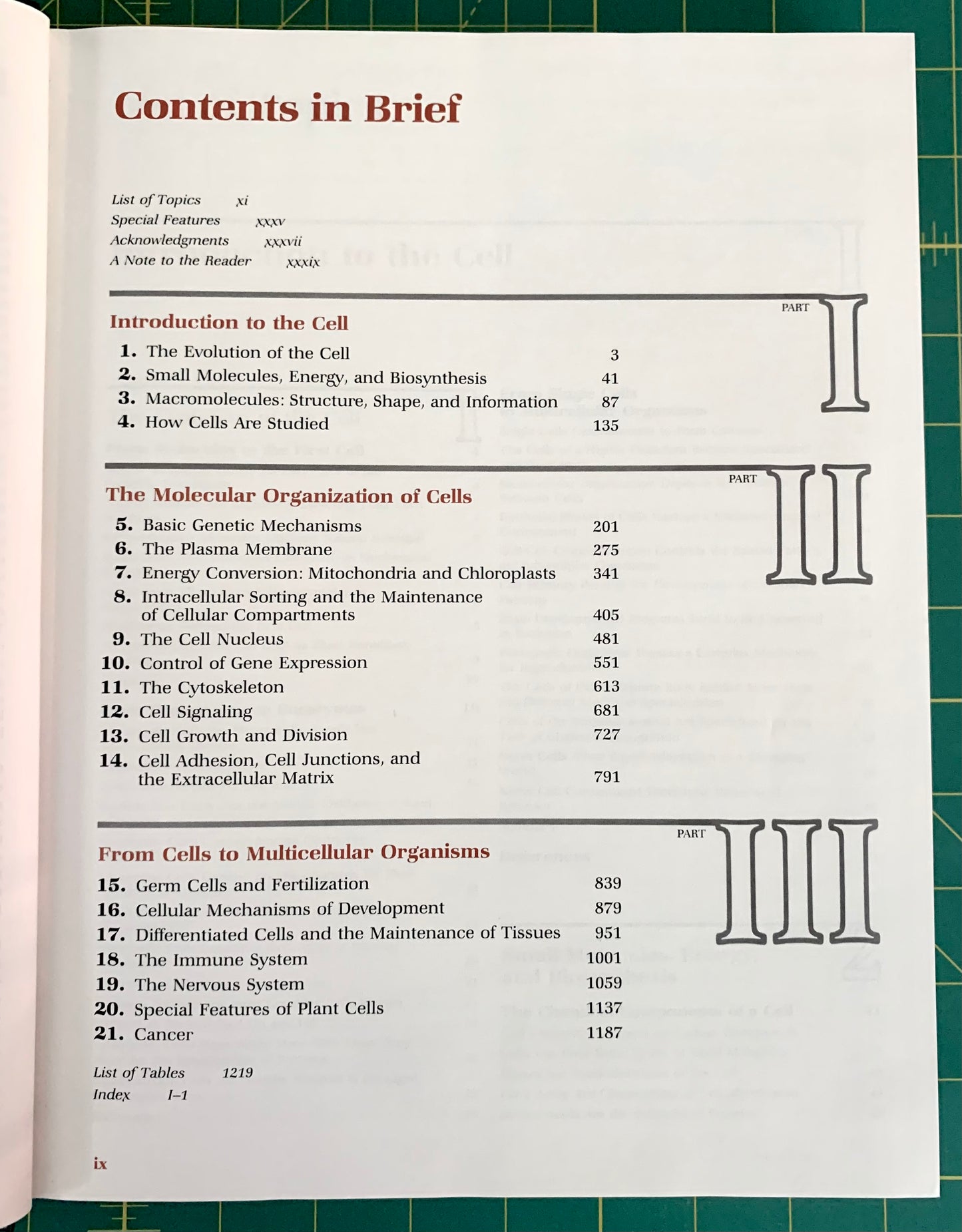 A printed table of contents page from a book or booklet titled 'Contents in Brief', photographed flat on a green grid cutting mat. The page is mostly white with black text and red headings, plus small red and blue section markers.
[additional_image_link]